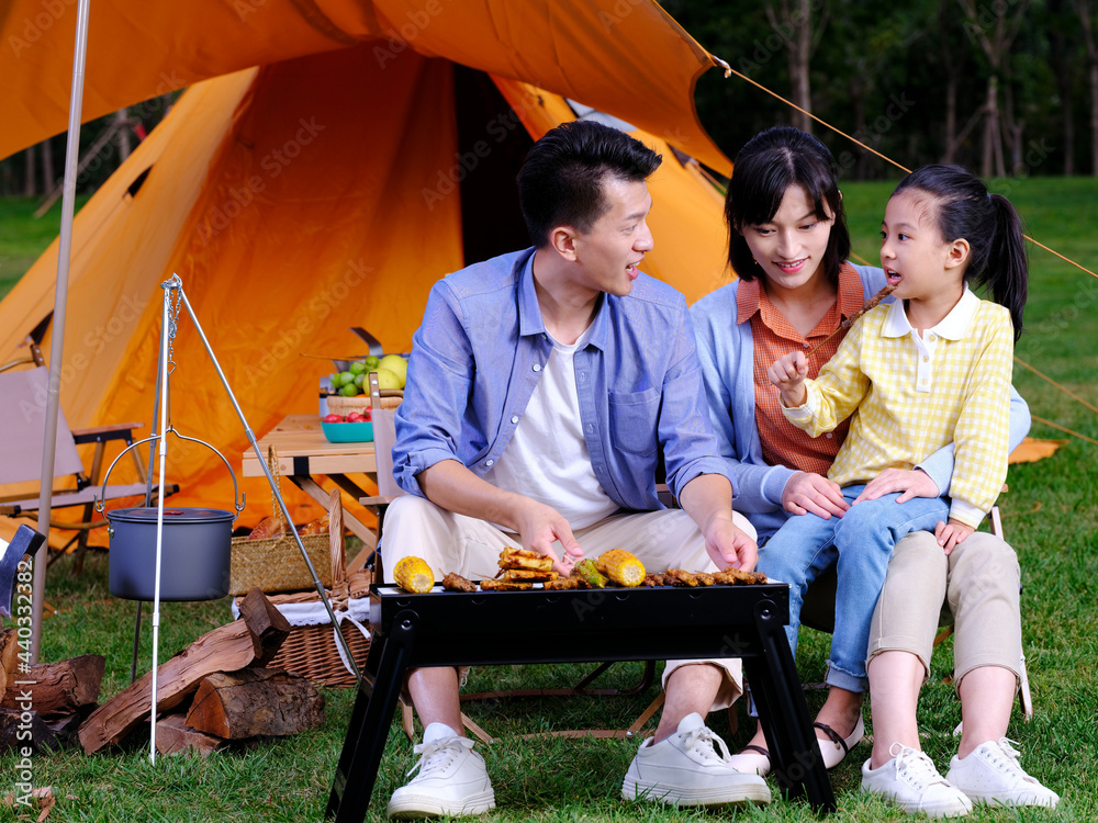 A happy family of three barbecue in the park