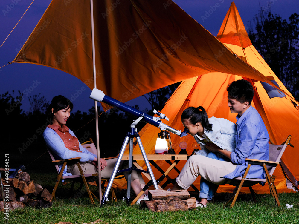 A happy family of three using telescopes outdoors