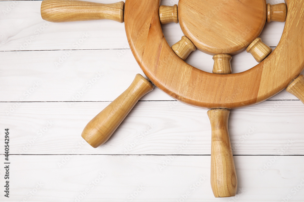 Ship helm on white wooden background