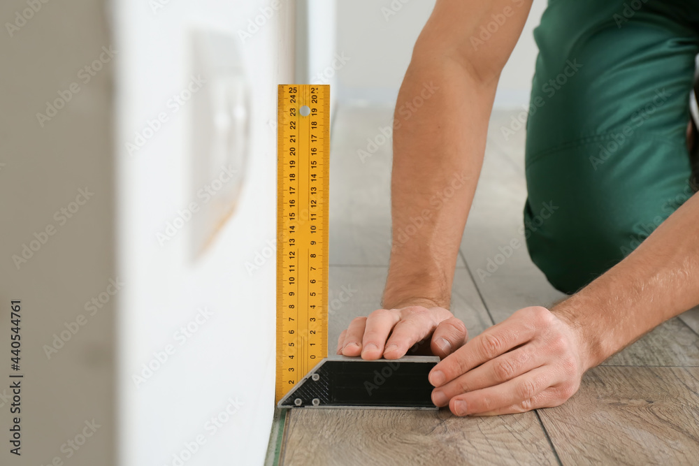 Carpenter taking measurements in room