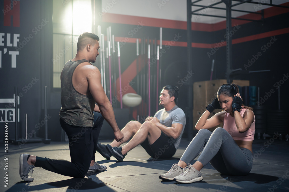 Asian Fitness trainer motivate sport people sit-up on floor in gym.