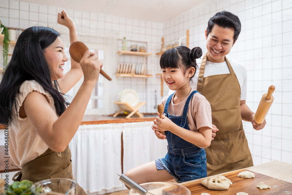 Asian happy family dancing in kitchen, kid enjoy cook food with parent