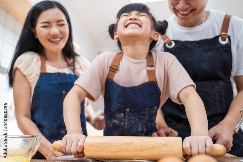 厨房里的幸福家庭父母教孩子在家里烤面包和食物