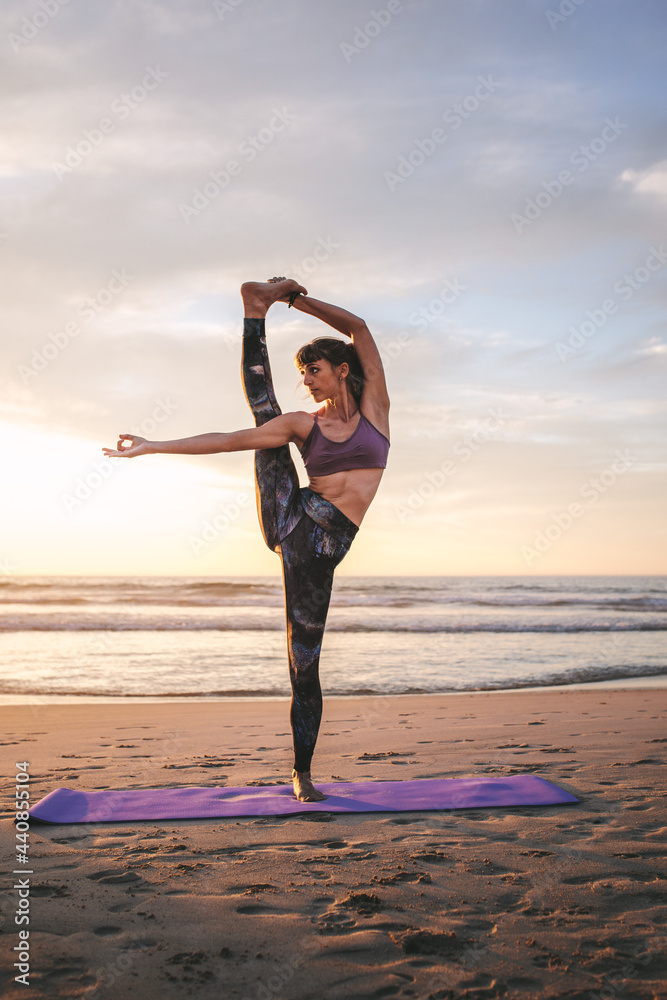 Young woman practicing yoga at beach