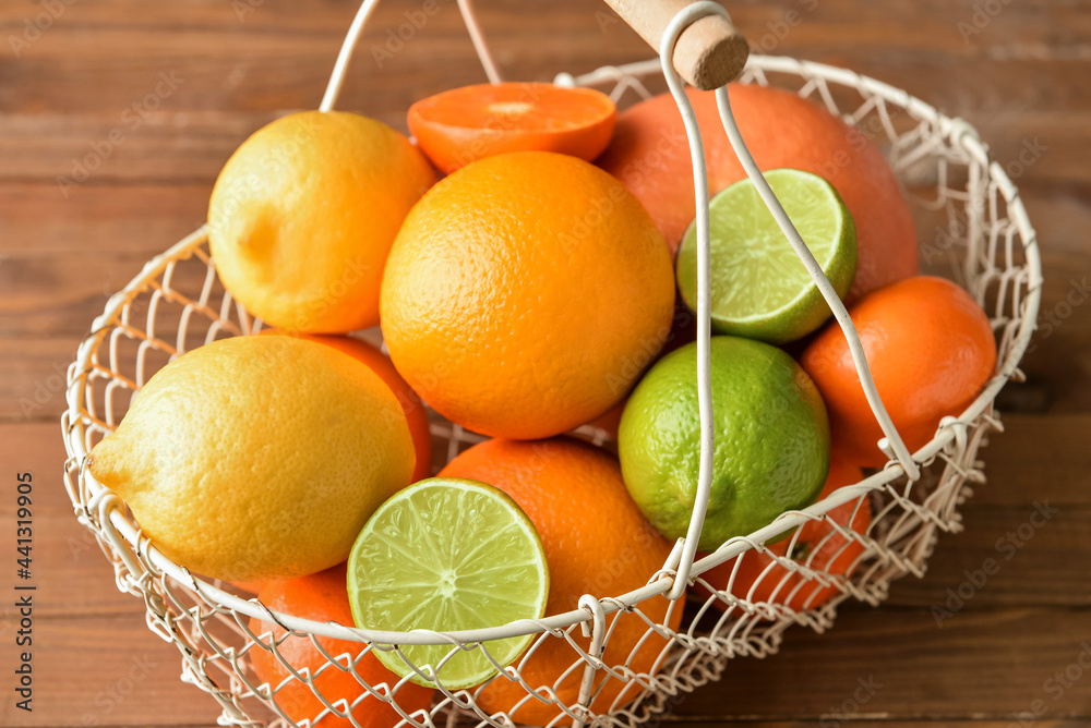 Basket with healthy citrus fruits on wooden background