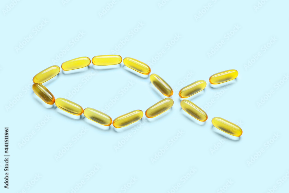 Fish made of oil capsules on color background