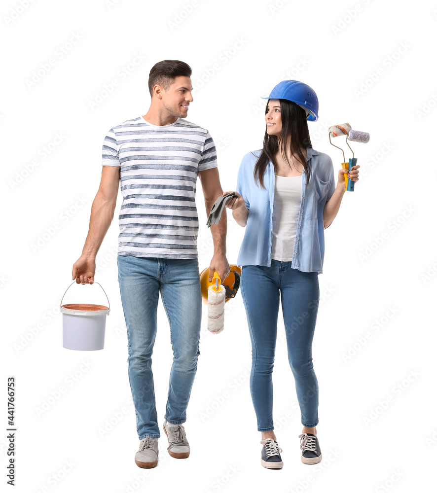 Young couple with rollers, gloves, bucket and cans of paint on white background