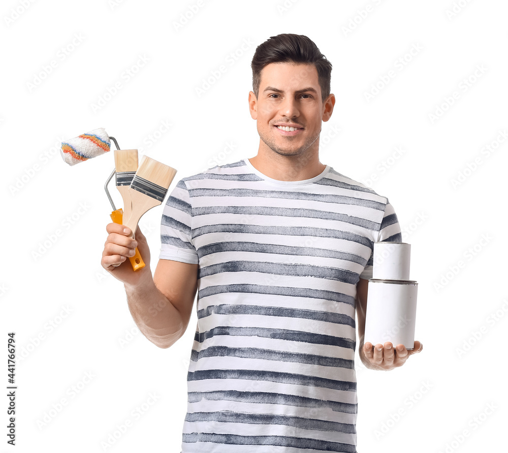 Young man with roller, brushes and cans of paint on white background