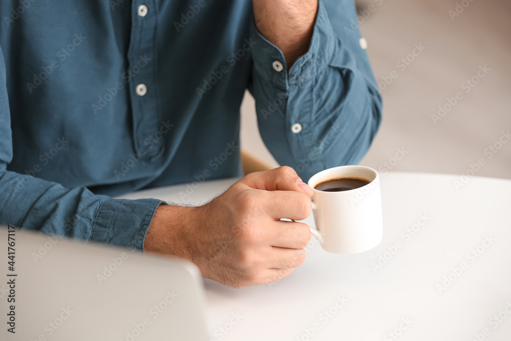 Young man drinking coffee in cafe, closeup