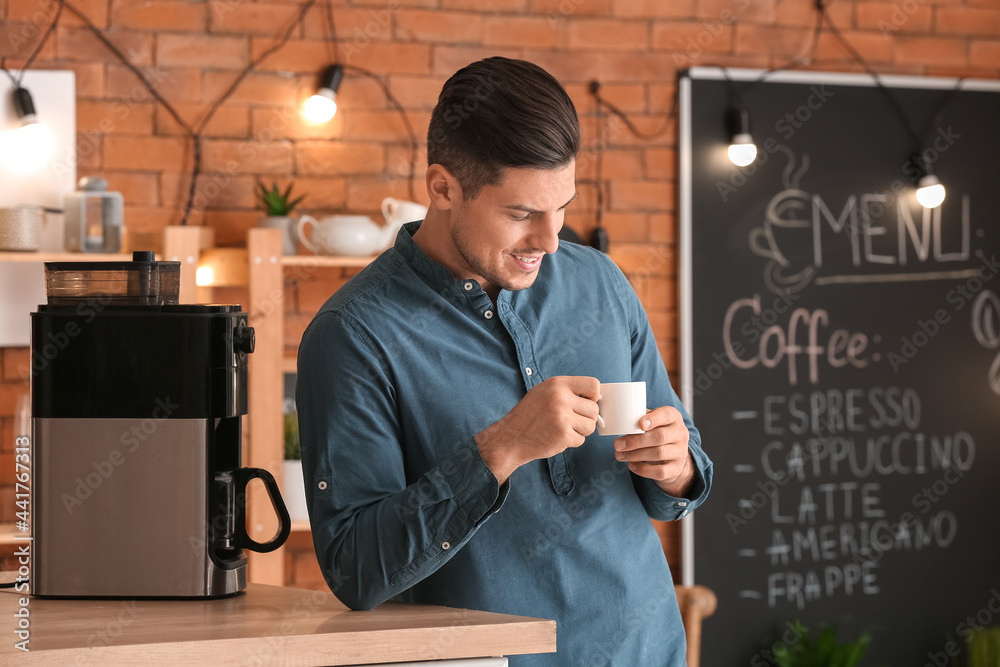 Handsome young man drinking coffee in cafe