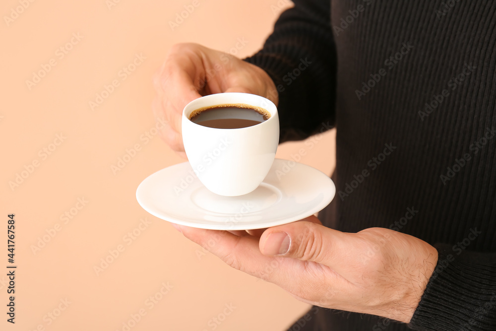 Young man drinking coffee on color background, closeup