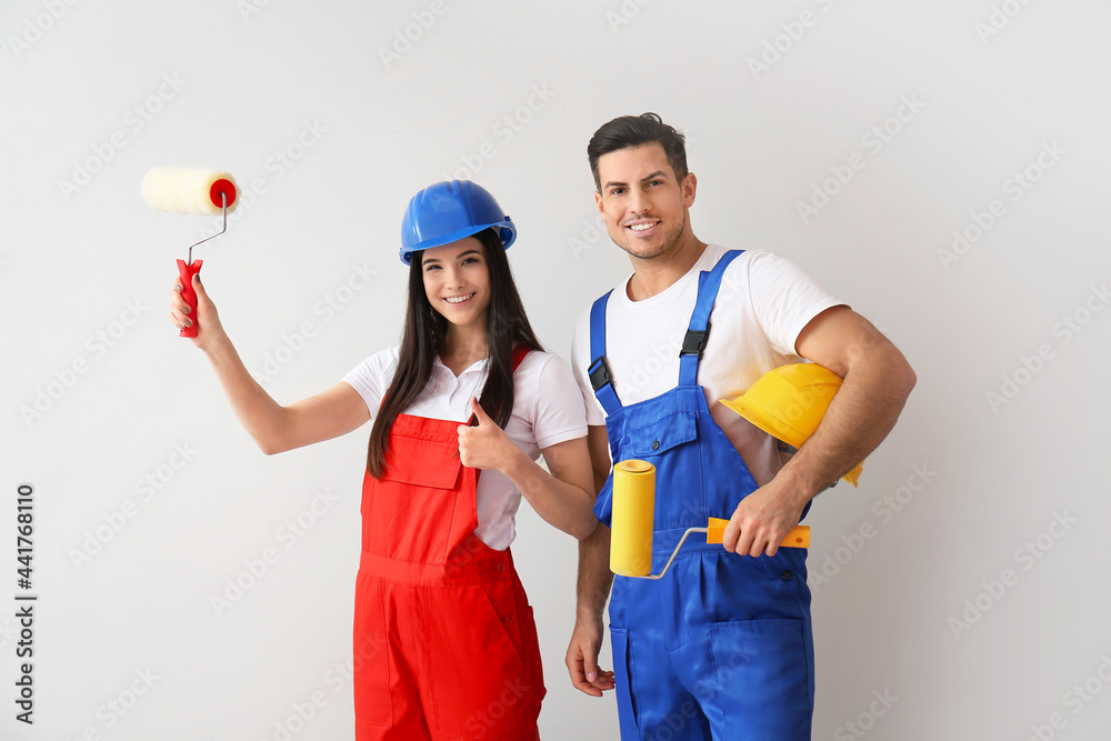 Young couple with rollers and hardhats on white background