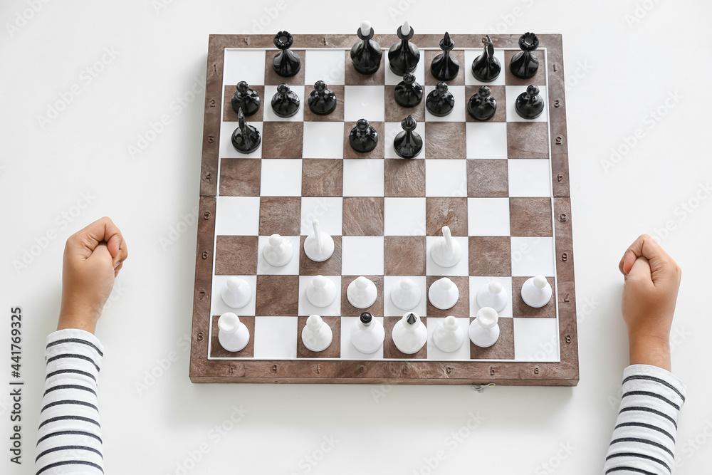 Cute African-American boy playing chess at home, top view