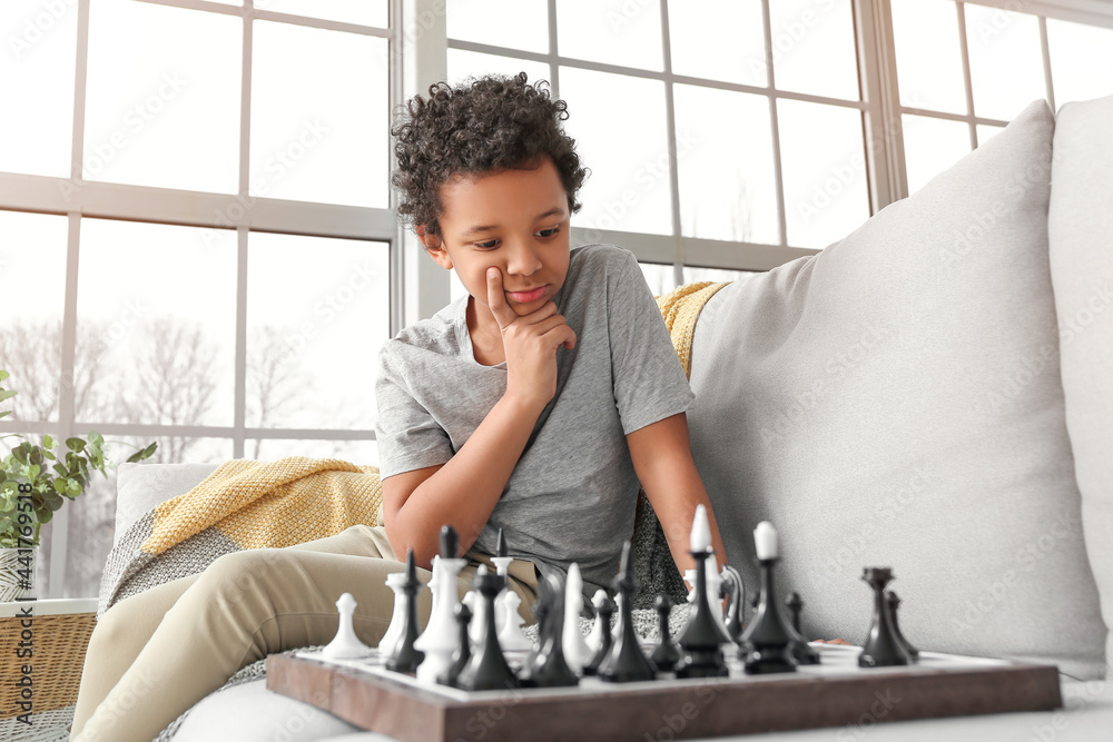 Cute African-American boy playing chess at home