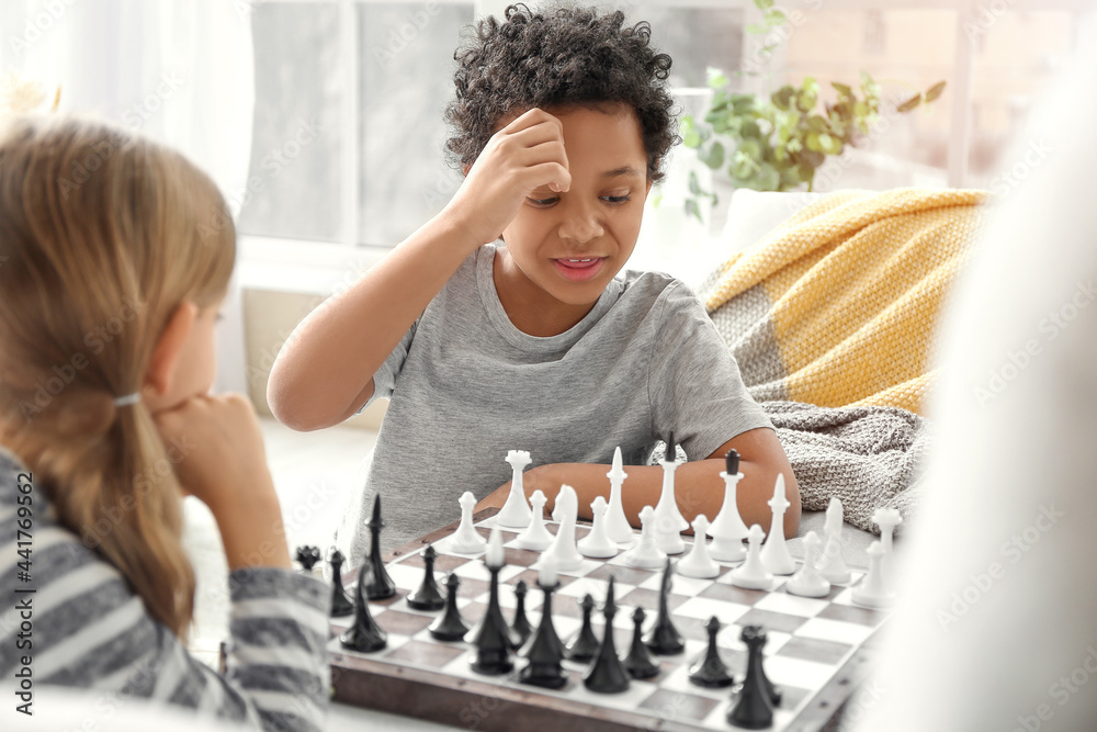 Cute children playing chess at home