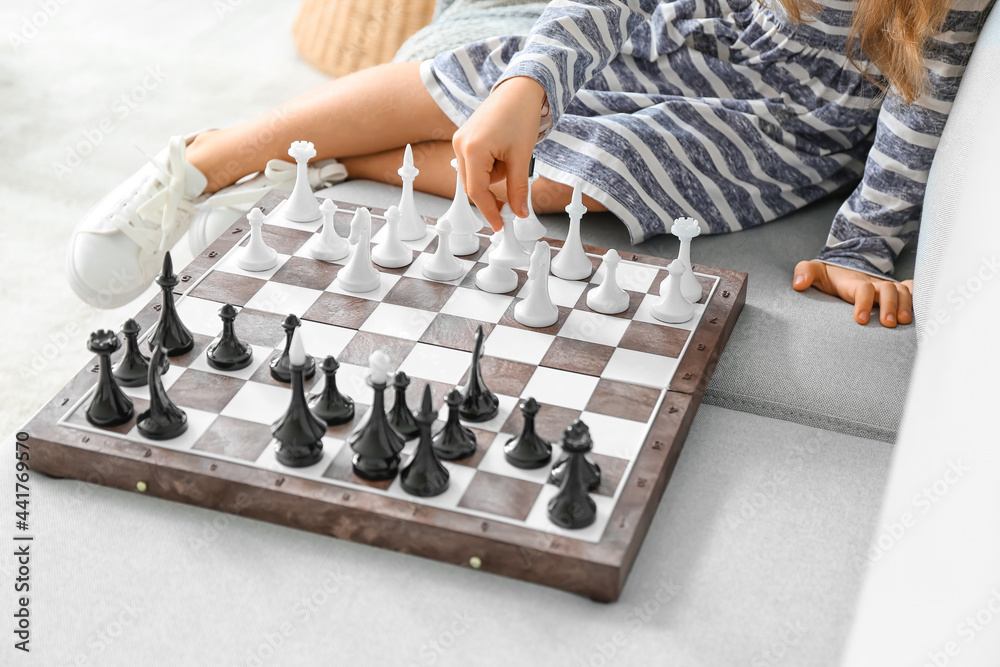 Cute little girl playing chess at home