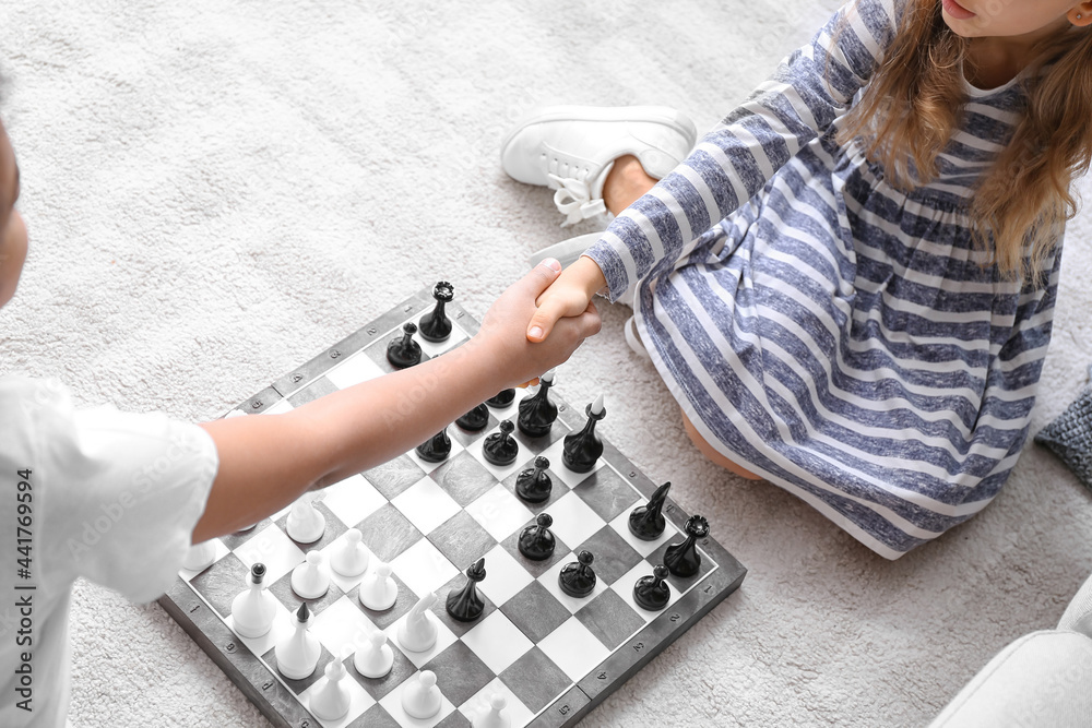 Cute children playing chess at home