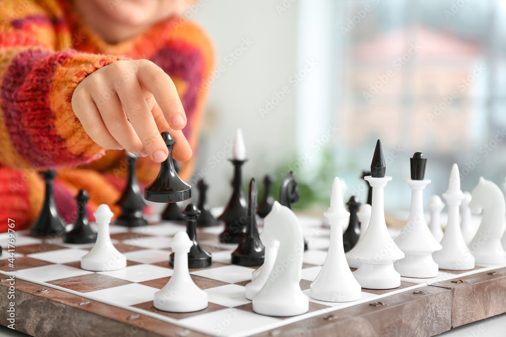 Cute little girl playing chess at home, closeup