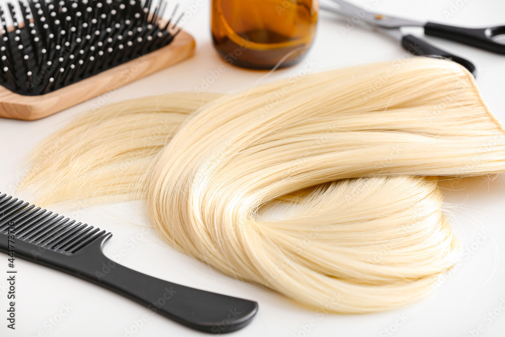 Barbers tools and strand of blonde hair on table, closeup