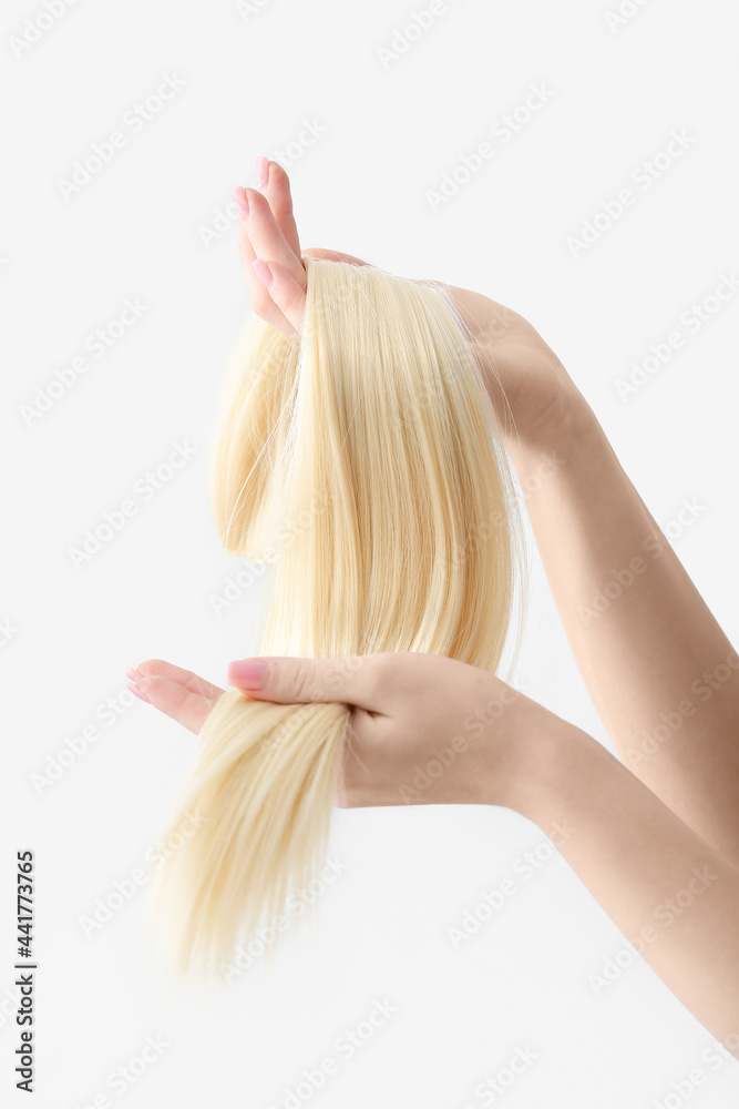 Woman with strand of blonde hair on white background