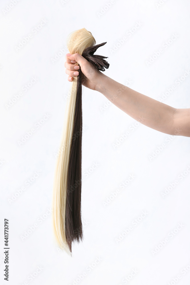 Woman with strands of blonde and brunette hair on white background