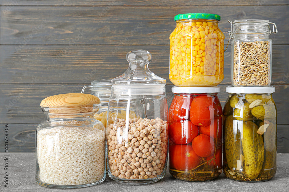 Glass jars with different products on dark wooden background