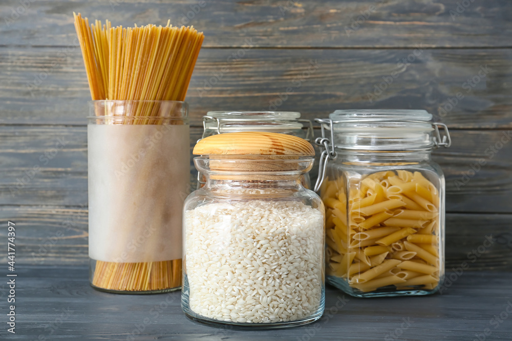 Glass jars with different products on dark wooden background