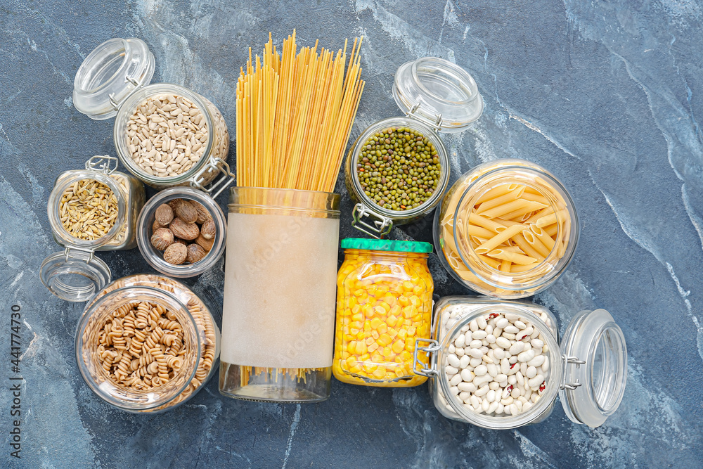 Glass jars with different products on color background