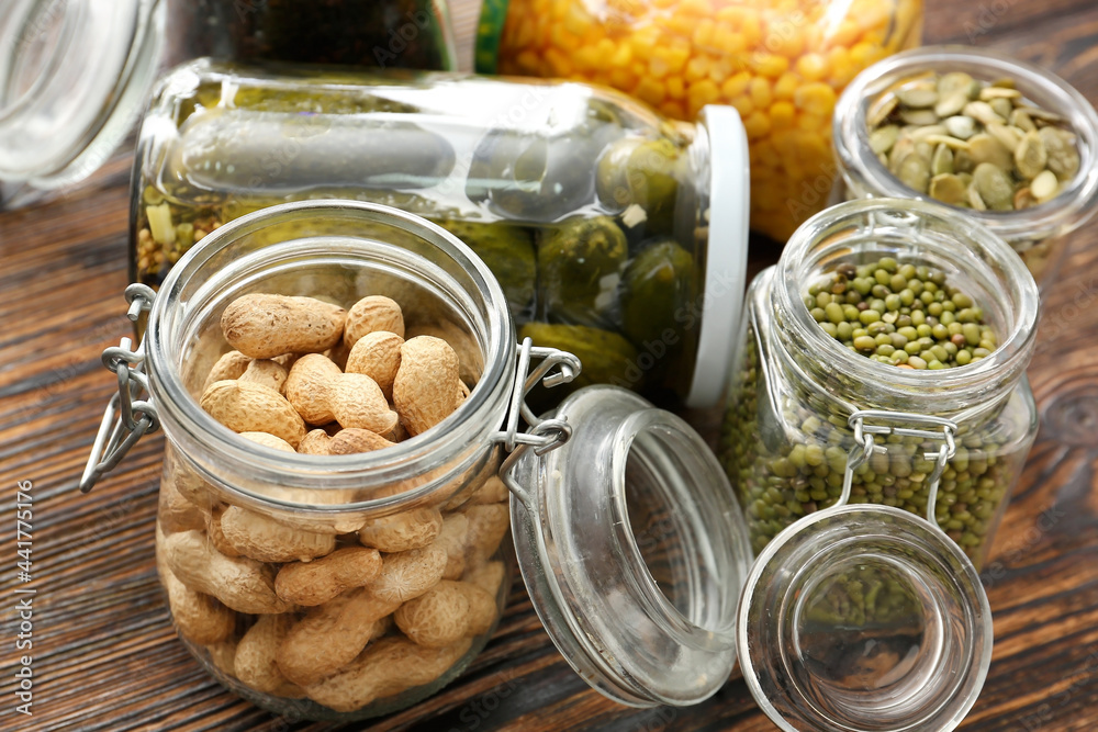 Glass jars with different products on wooden background