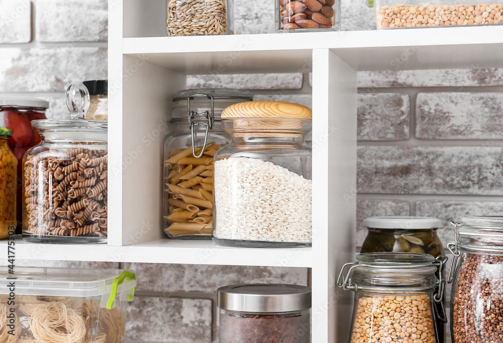 Jars with different products on shelves near brick wall