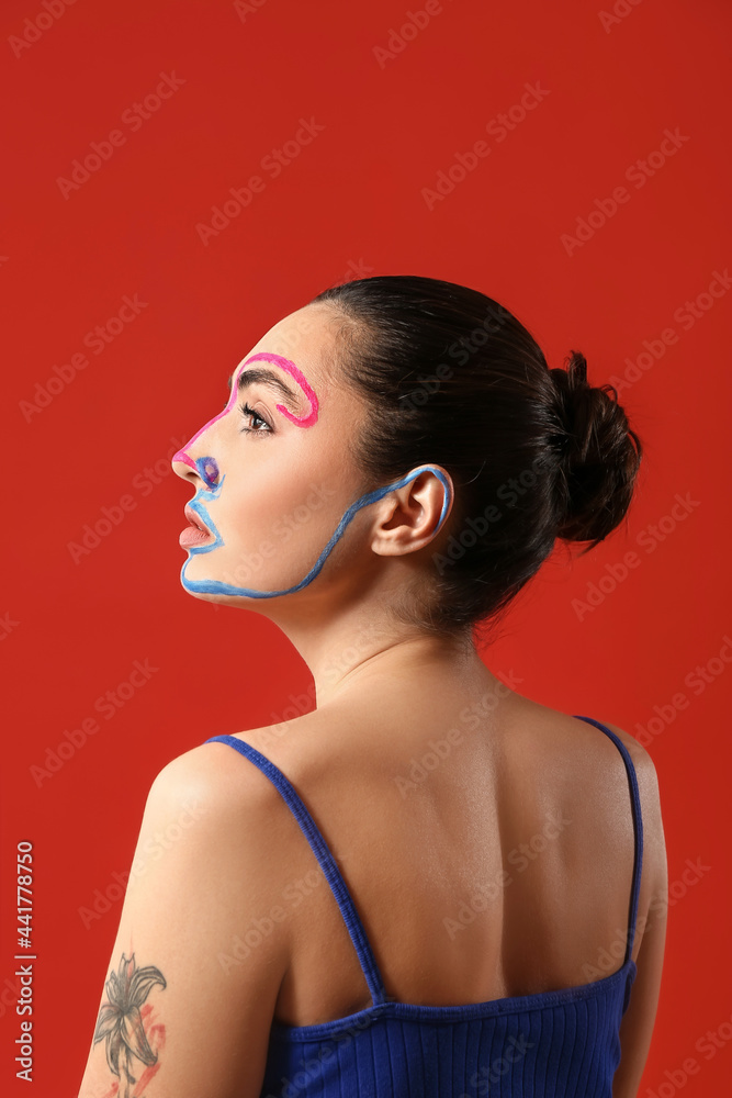 Beautiful young woman with paint on her face against color background