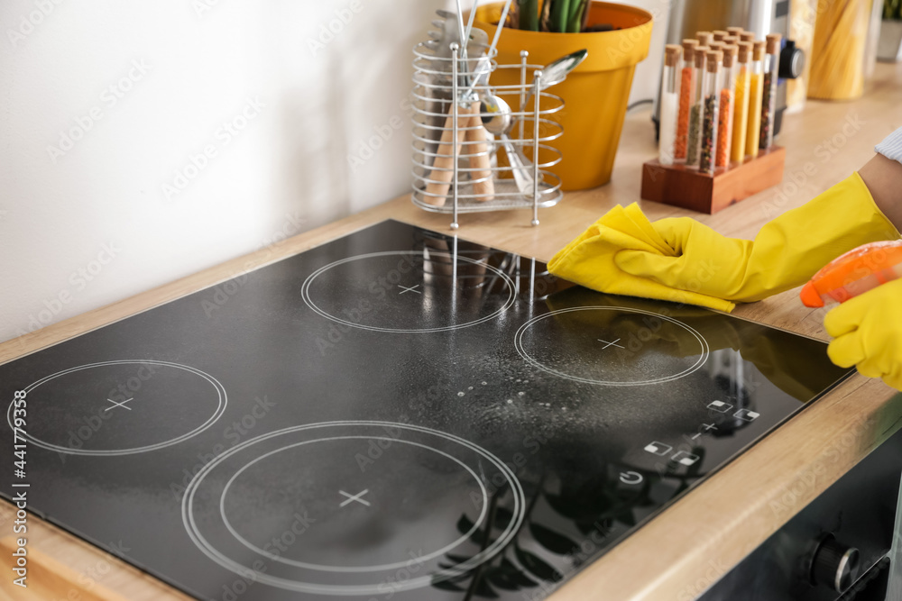 Woman cleaning stove in kitchen, closeup