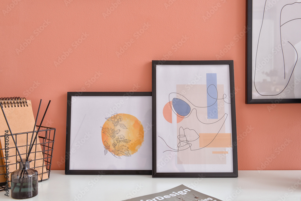 Stylish pictures on table near color wall