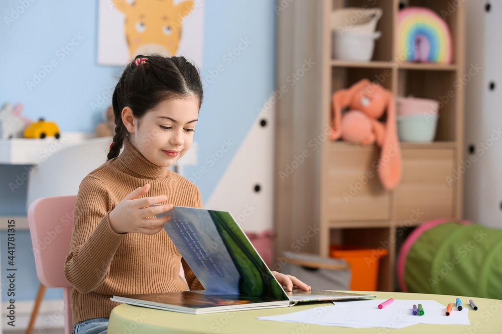 Little girl reading book at home