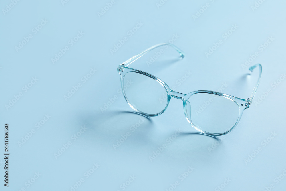 Stylish eyeglasses on color background