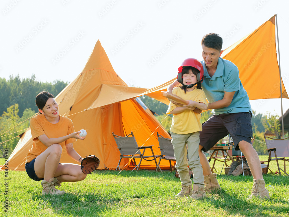 Happy family of three playing baseball in the park