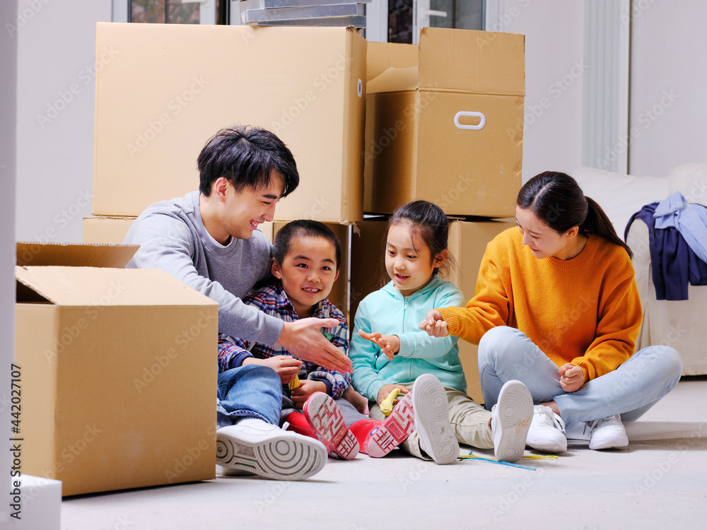 Happy family of four sitting on the ground playing