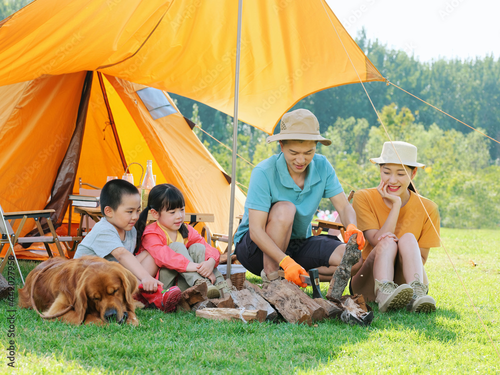 Happy family of four and dog camping out