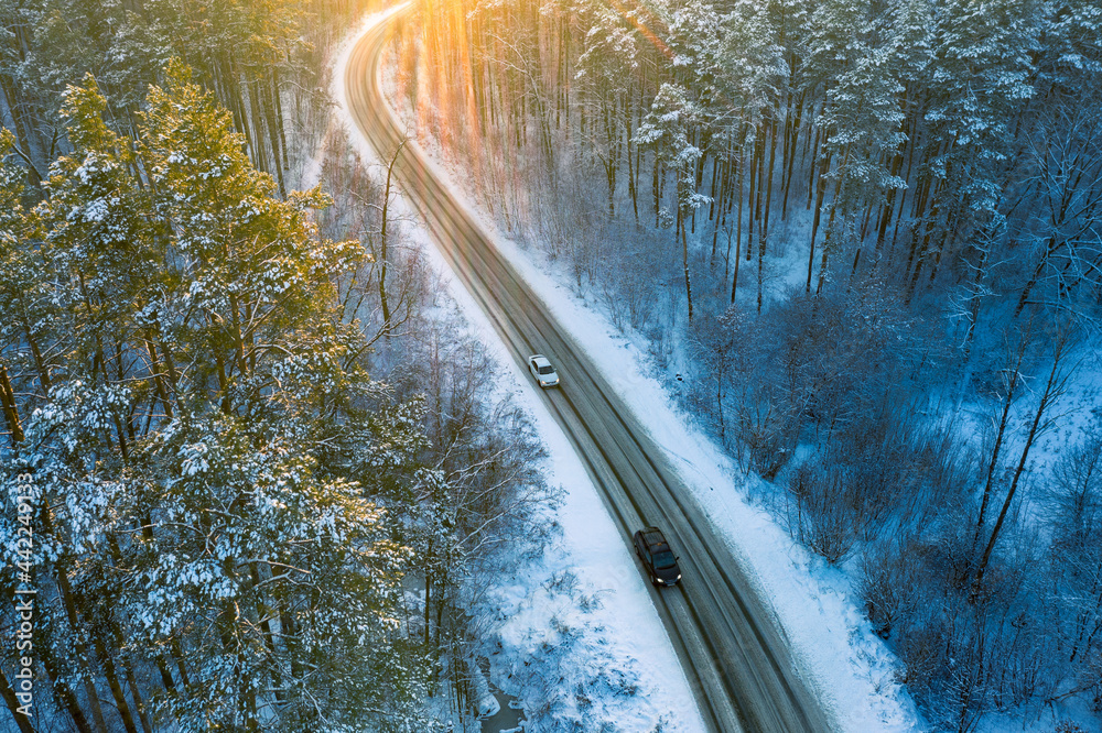 日落时分，雪林中央的冬日公路鸟瞰图