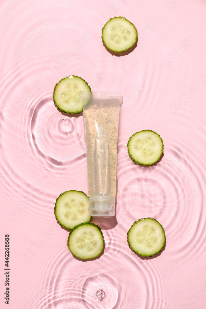 Tube of cosmetic product and slices of cucumber in water on color background