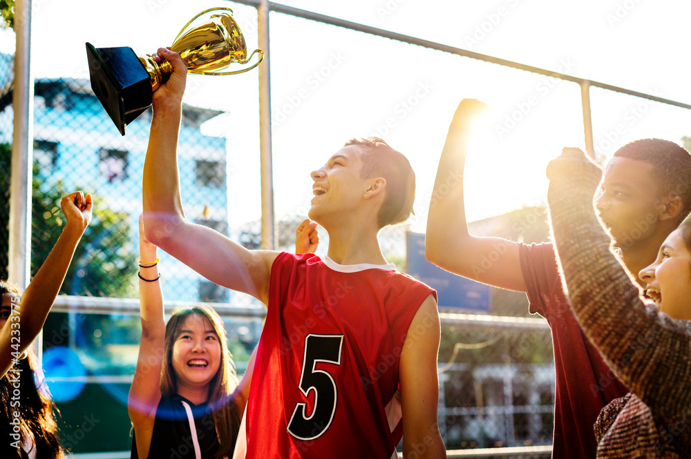 Group of teenagers cheering with trophy victory and teamwork concept