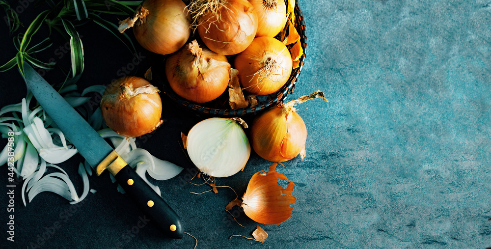 Cebollas y rodajas sobre tabla de cortar de madera y cesto de mimbre. Fondo de alimentos saludables.