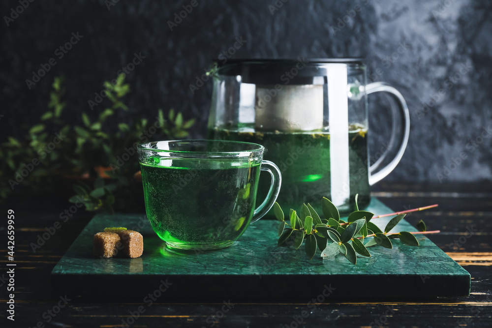 桌上有茶壶和一杯热的绿色饮料