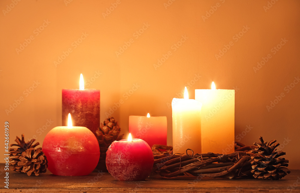 Burning candles and decor on table near color wall