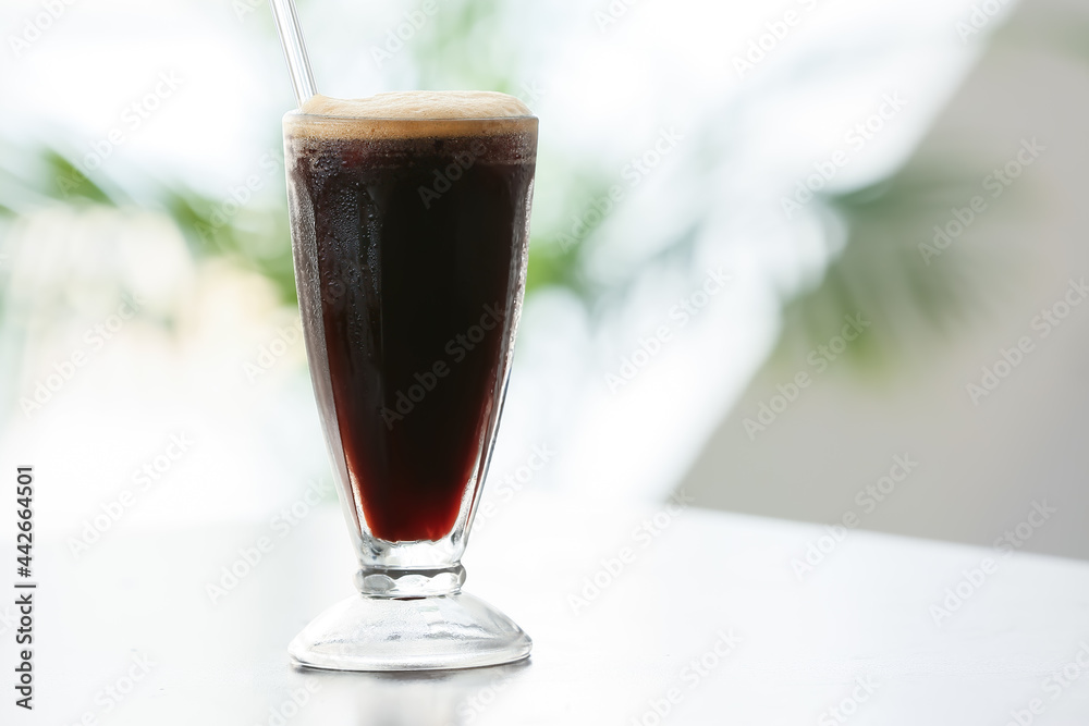 Glass of tasty iced coffee on table