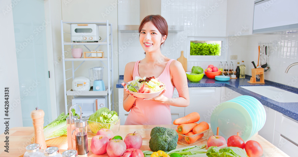 female holding salad in kitchen