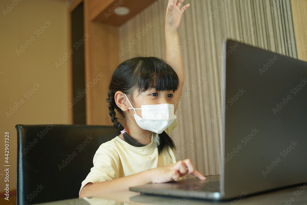 Asian kid girl school pupil wearing protective medical mask studying online from home watching web c