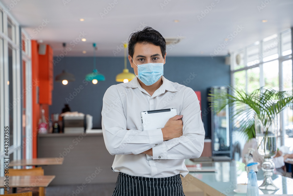 Waitress while wearing protective face mask working at coffee shop.