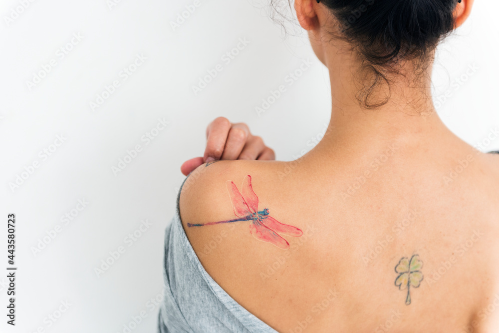 A woman is showing her tattoo on her back