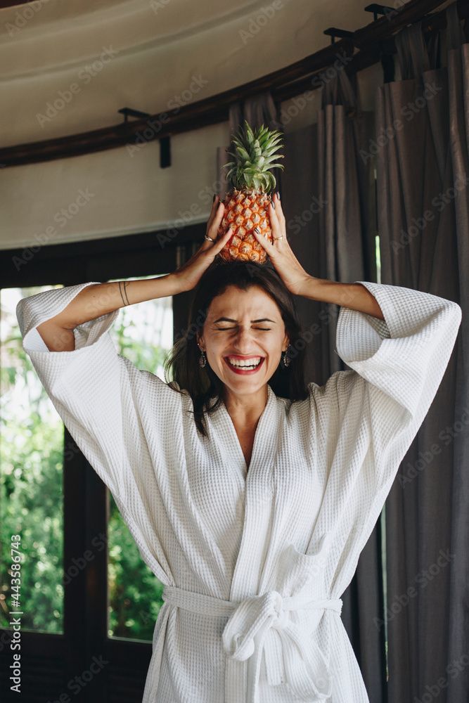 Woman in a bathrobe holding a pineapple